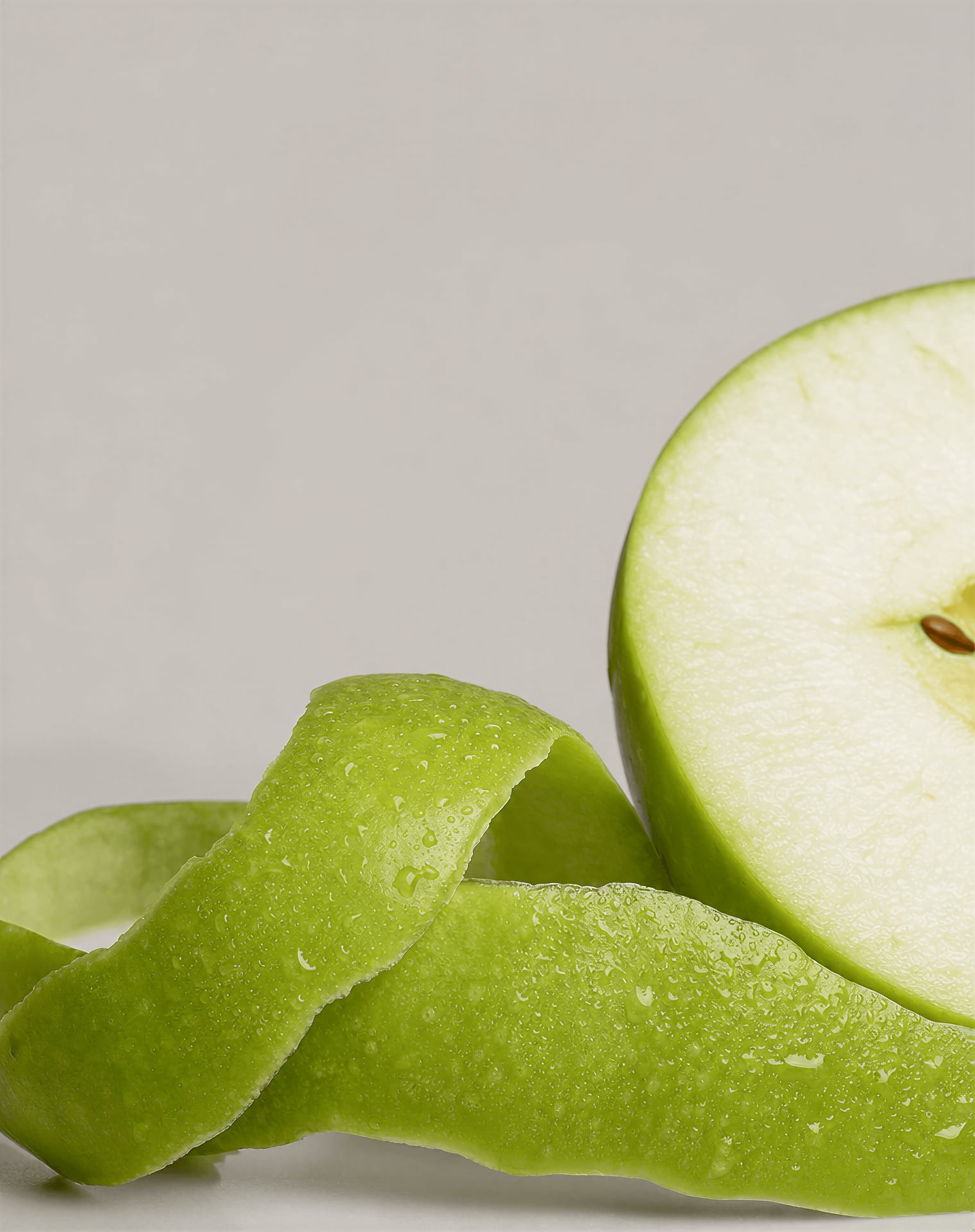 Close view of green apple peel and a sliced apple with waxy skin texture.