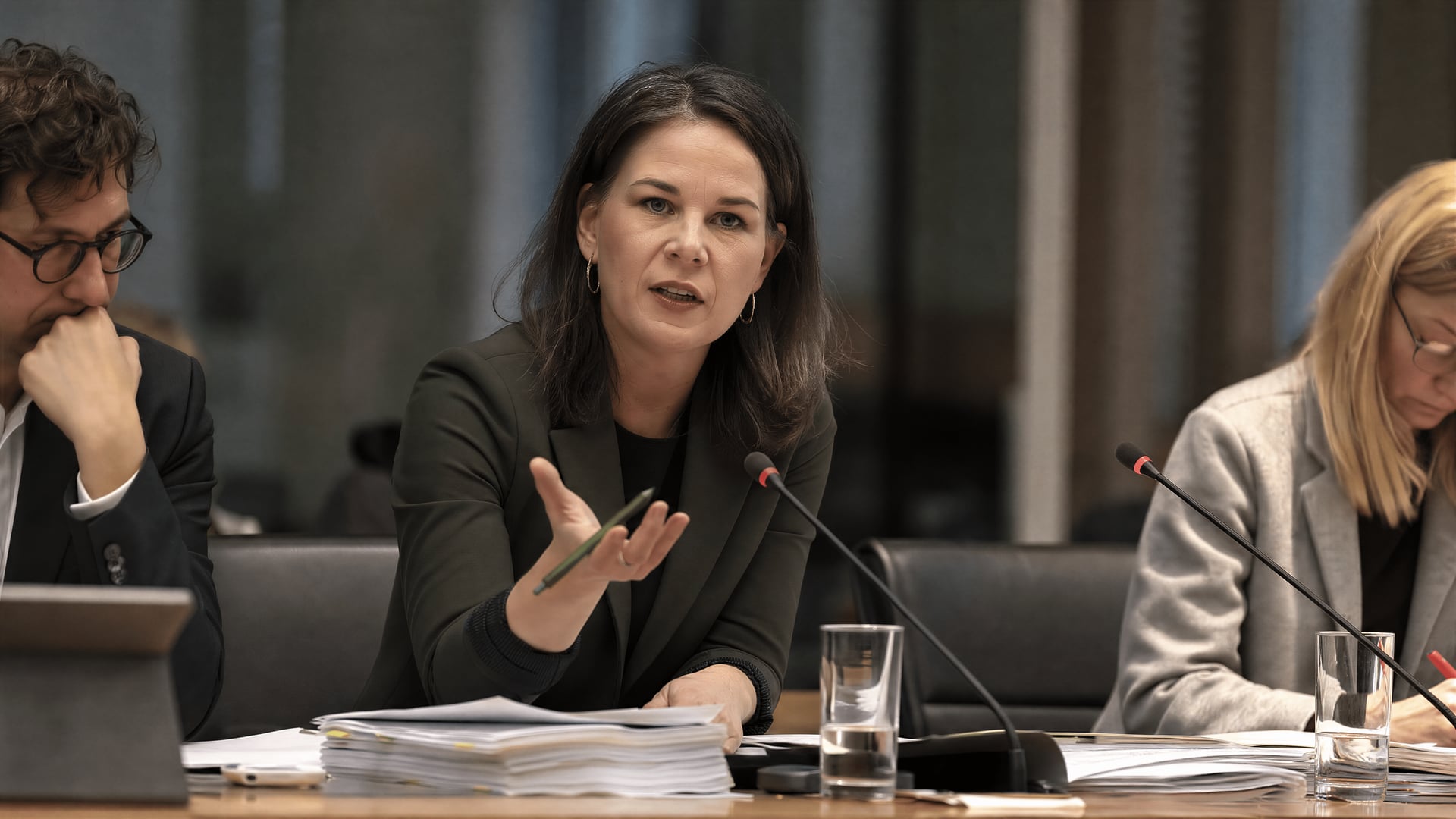 Bundestag bizottsági ülés, az asztalon a Cannabis-törvény értékelését tartalmazó iratok és mikrofonok.