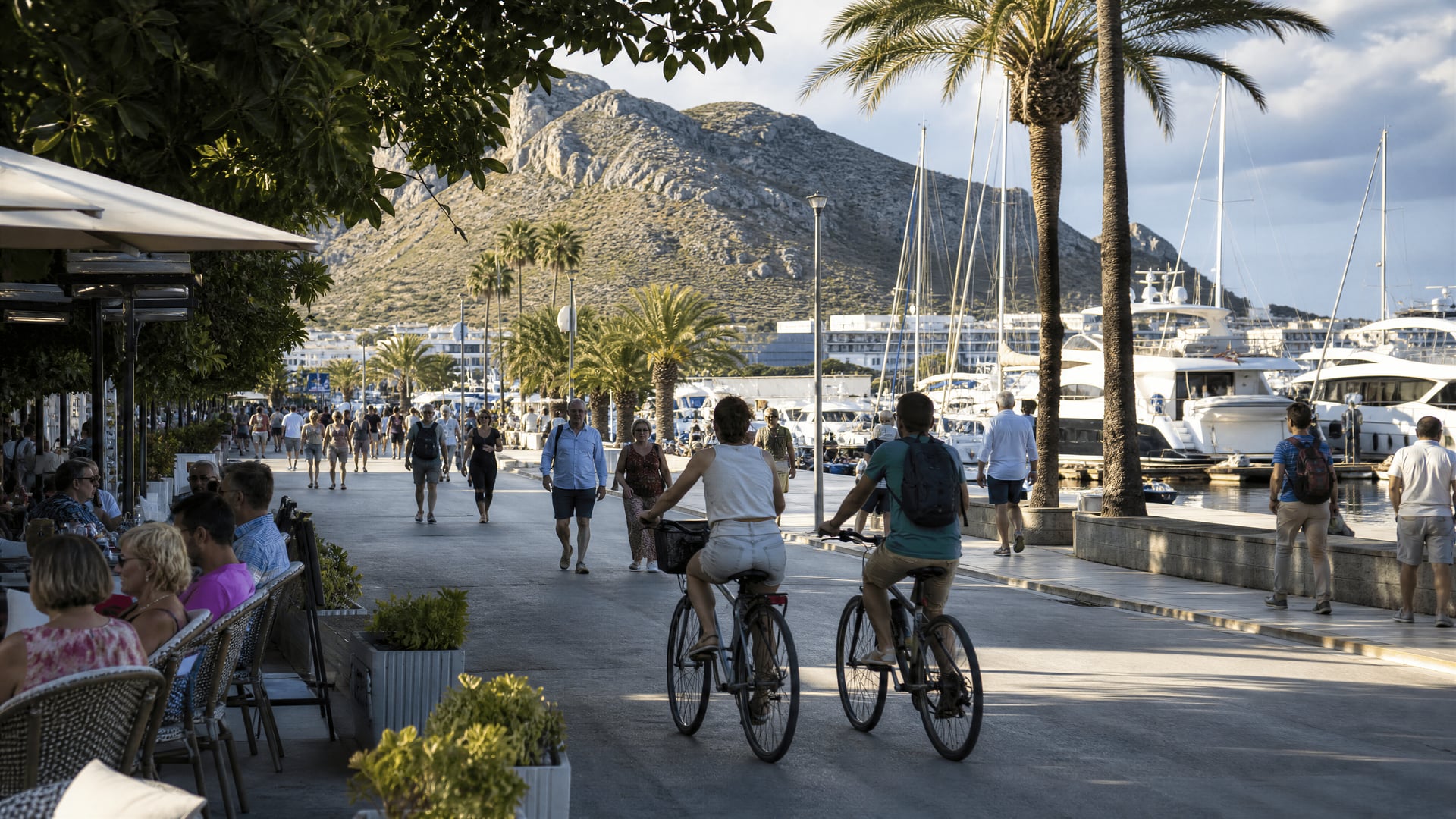 Port de Pollença marina walk with cyclists and local street life