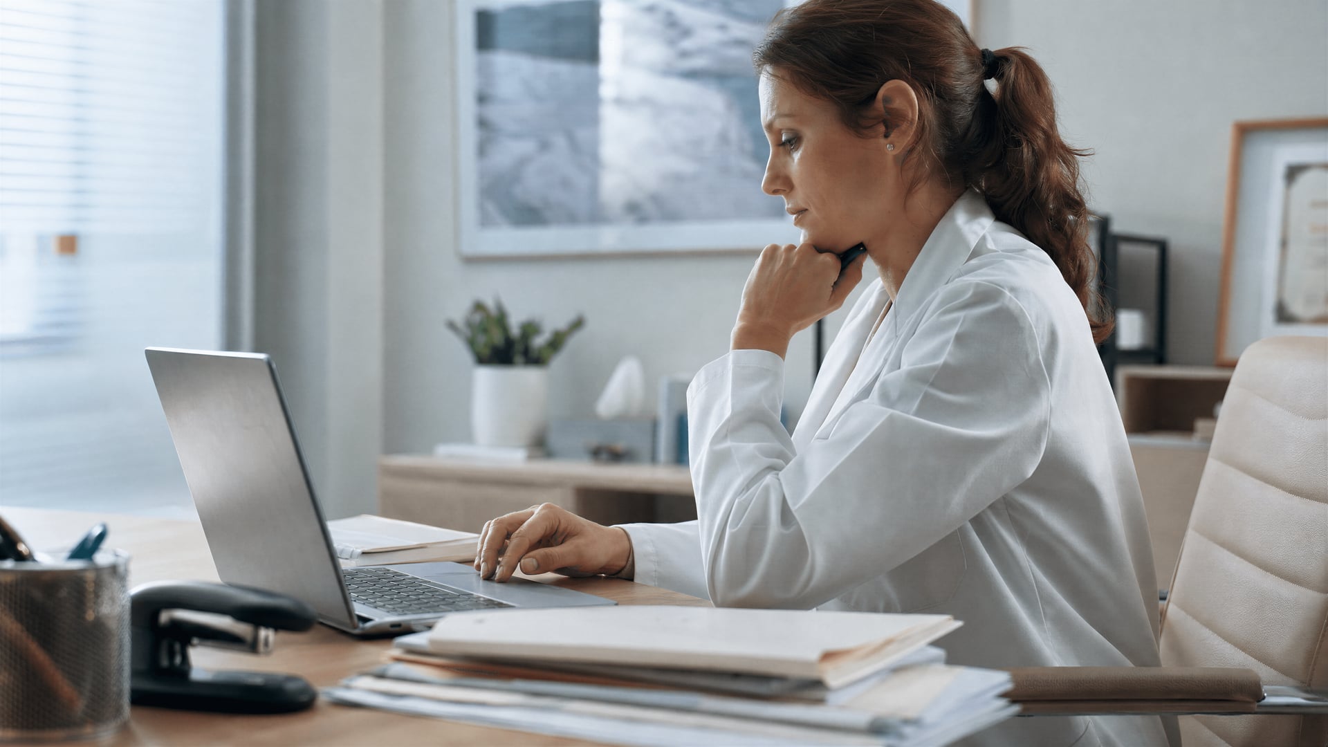 Kliniker in einem Büro einer Privatklinik im Vereinigten Königreich prüft auf einem Laptop Verschreibungsunterlagen zu medizinischem Cannabis