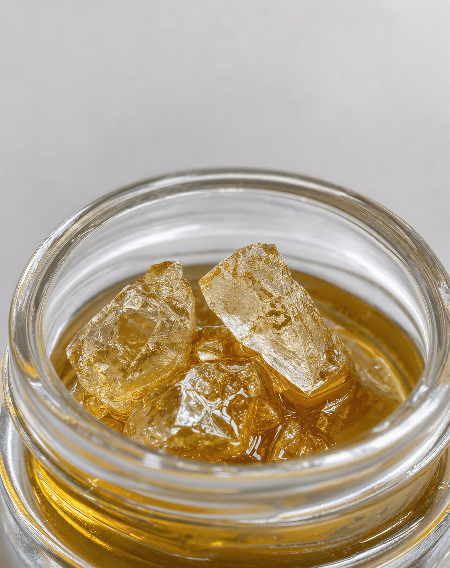 Macro view of THCA crystals sitting in amber terpene sauce inside a glass jar.