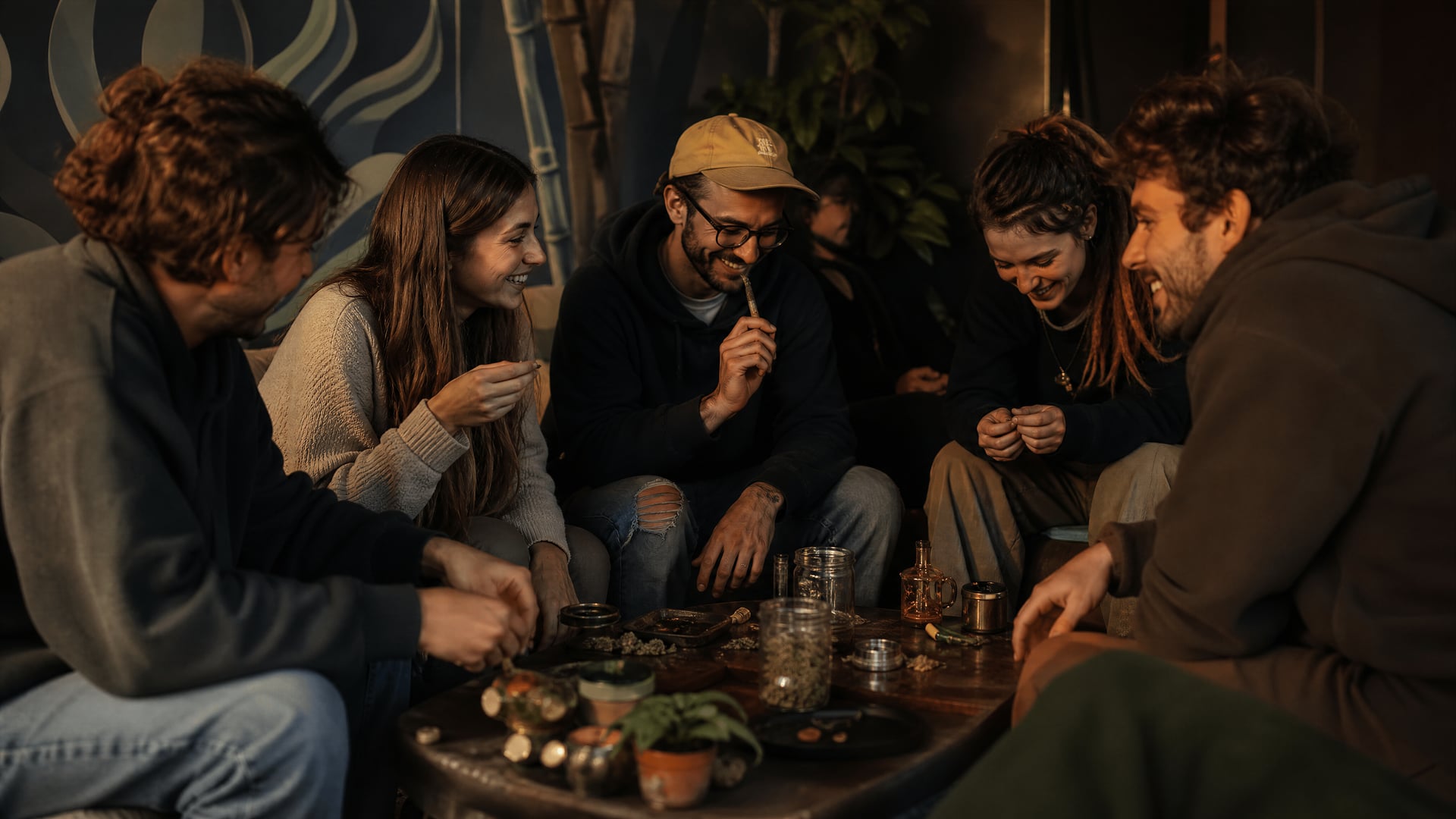 Members chatting at a Llucmajor cannabis social club table with low, relaxed lighting