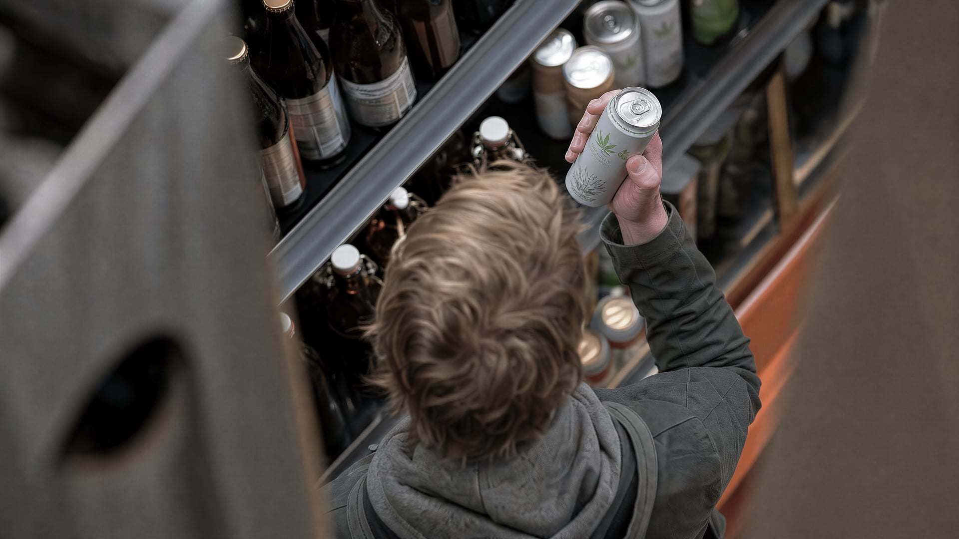 A grocery-store beverage aisle with THC drinks beside beer bottles and a shopper.