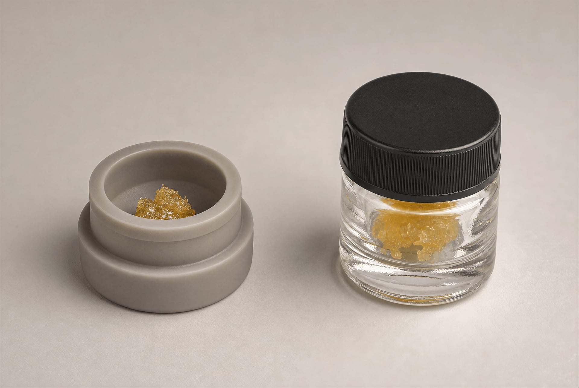 Cannabis concentrate shown in a silicone puck beside a small airtight glass jar.