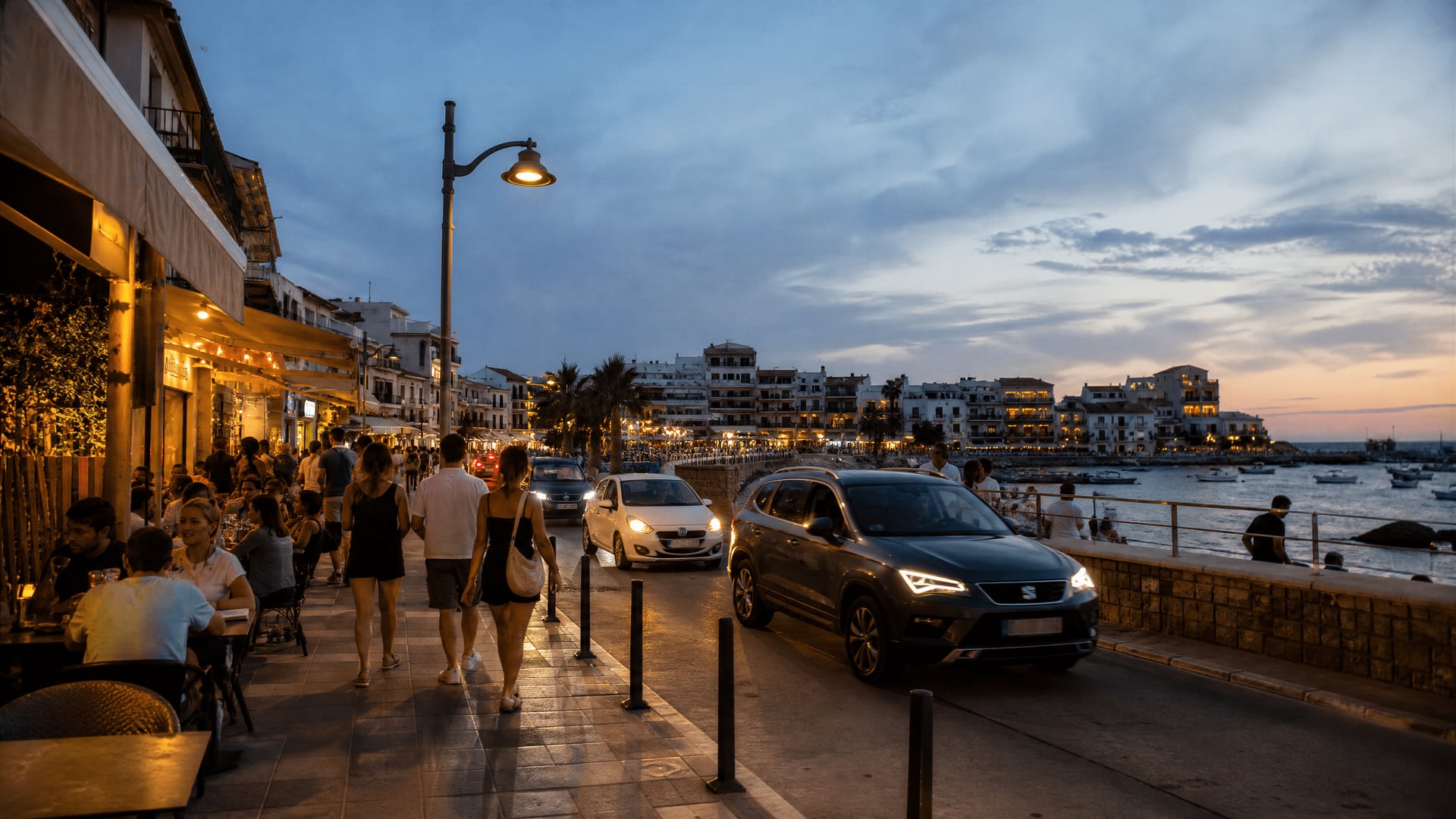 Passeggiata sul lungomare di Cala Ratjada con traffico serale e atmosfera di quartiere dei club della cannabis